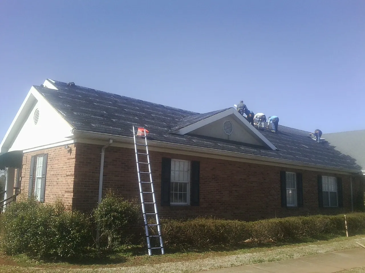 Crew tearing shingles off a brick ranch roof with a ladder set — Metal Roof Repair work by our crew in Garden Grove