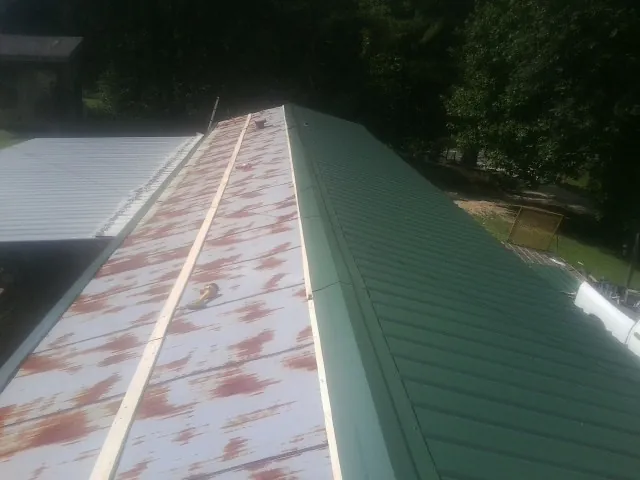 Old rusted panels beside newly installed green metal roofing — Wind Damage Roof Repair by Roofing Brothers in Garden Grove