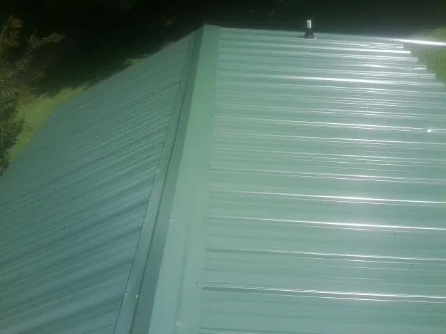 New green metal panels meeting at the ridge of a roof — Flat Roof Repair work by our crew in Garden Grove