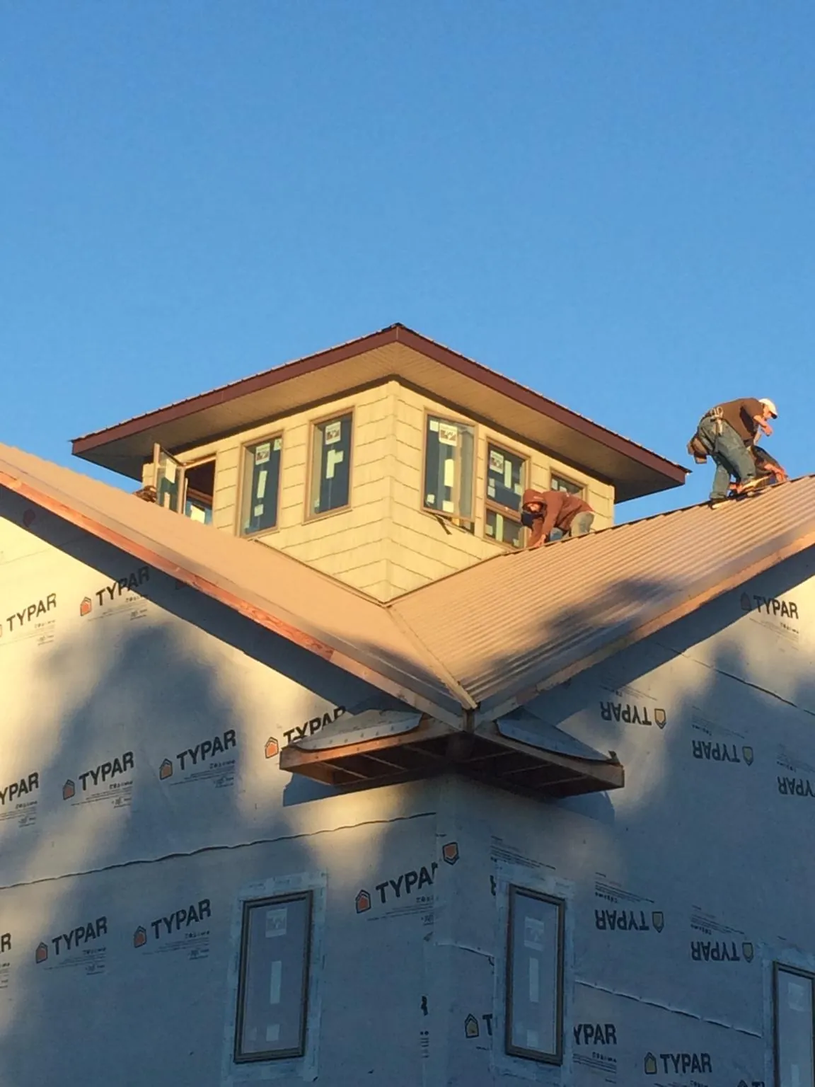 Roofers working around a rooftop cupola on a new metal roof at sunset — Roof Waterproofing in Garden Grove by Roofing Brothers